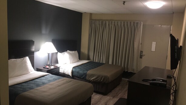 Una habitación de hotel con dos camas, un escritorio, un televisor y una lámpara.