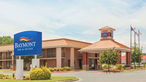 Edificio del Baymont Inn & Suites con un letrero llamativo, fachada de ladrillo y una pequeña torre con una bandera.