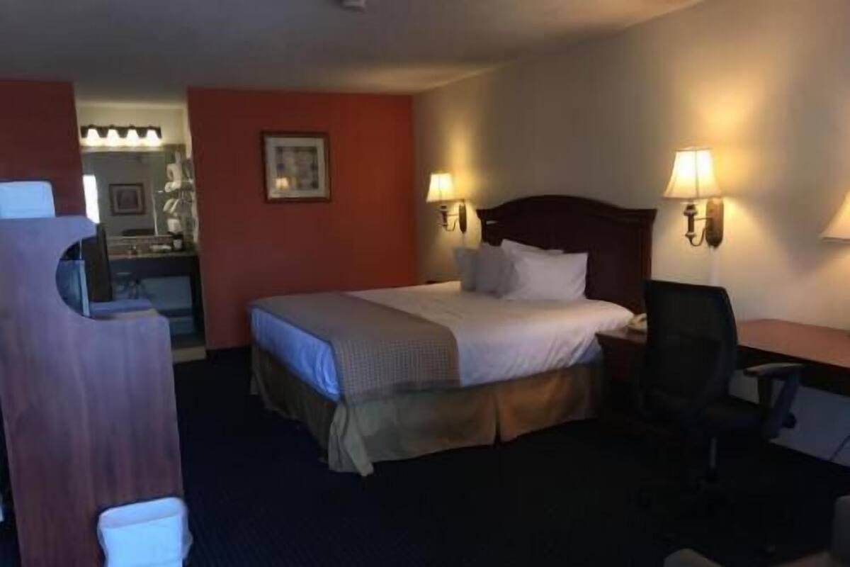 Una habitación de hotel con cama, lámparas de noche, escritorio y una silla.