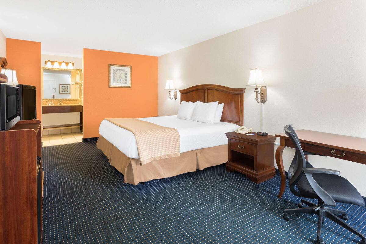Habitación de hotel con cama, escritorio, silla y televisor.