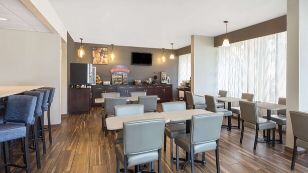 Un restaurante moderno con barra, diversas opciones de asientos y un televisor de pantalla plana en la pared.
