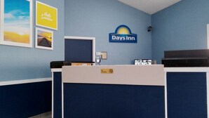 Ein Empfangstisch im Days Inn mit blau-weißer Gestaltung, einem Rauchverbotsschild und gerahmten Bildern an der Wand.