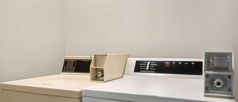 A laundry area with three washing machines and a dryer.
