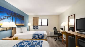 A hotel room with two beds, a desk with a computer, a TV, and a painting on the wall.