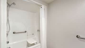A white bathroom with a bathtub, shower, and grab bars.
