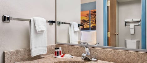 A bathroom with a granite countertop, a sink, a mirror, and a towel rack.