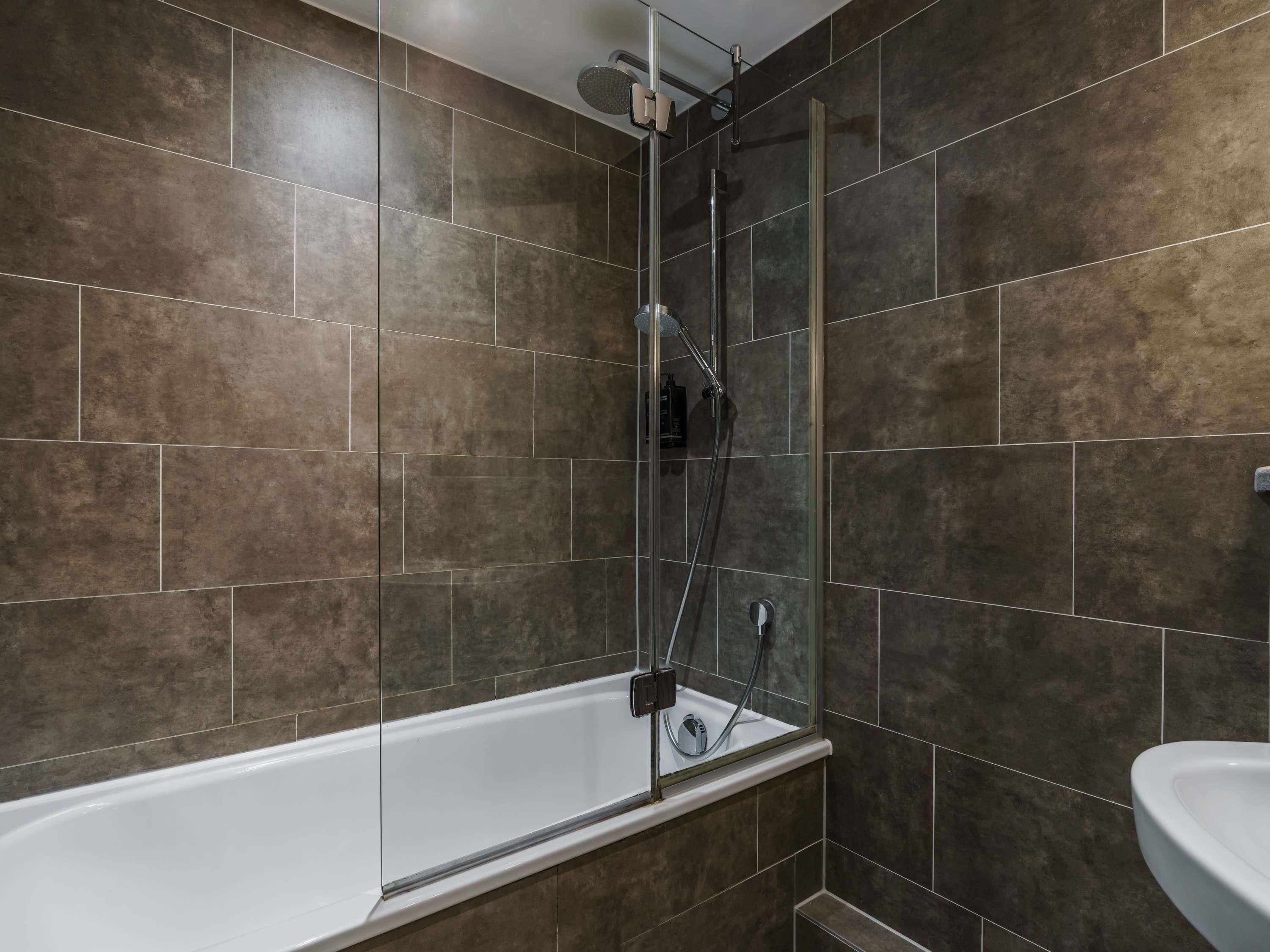 A bathroom with a glass-enclosed shower, a white bathtub, and a sink.