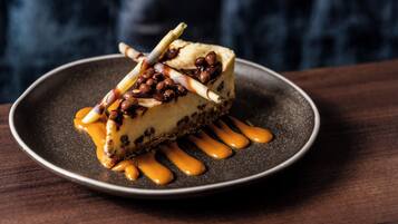 A slice of cheesecake with caramel sauce and nuts on a plate.
