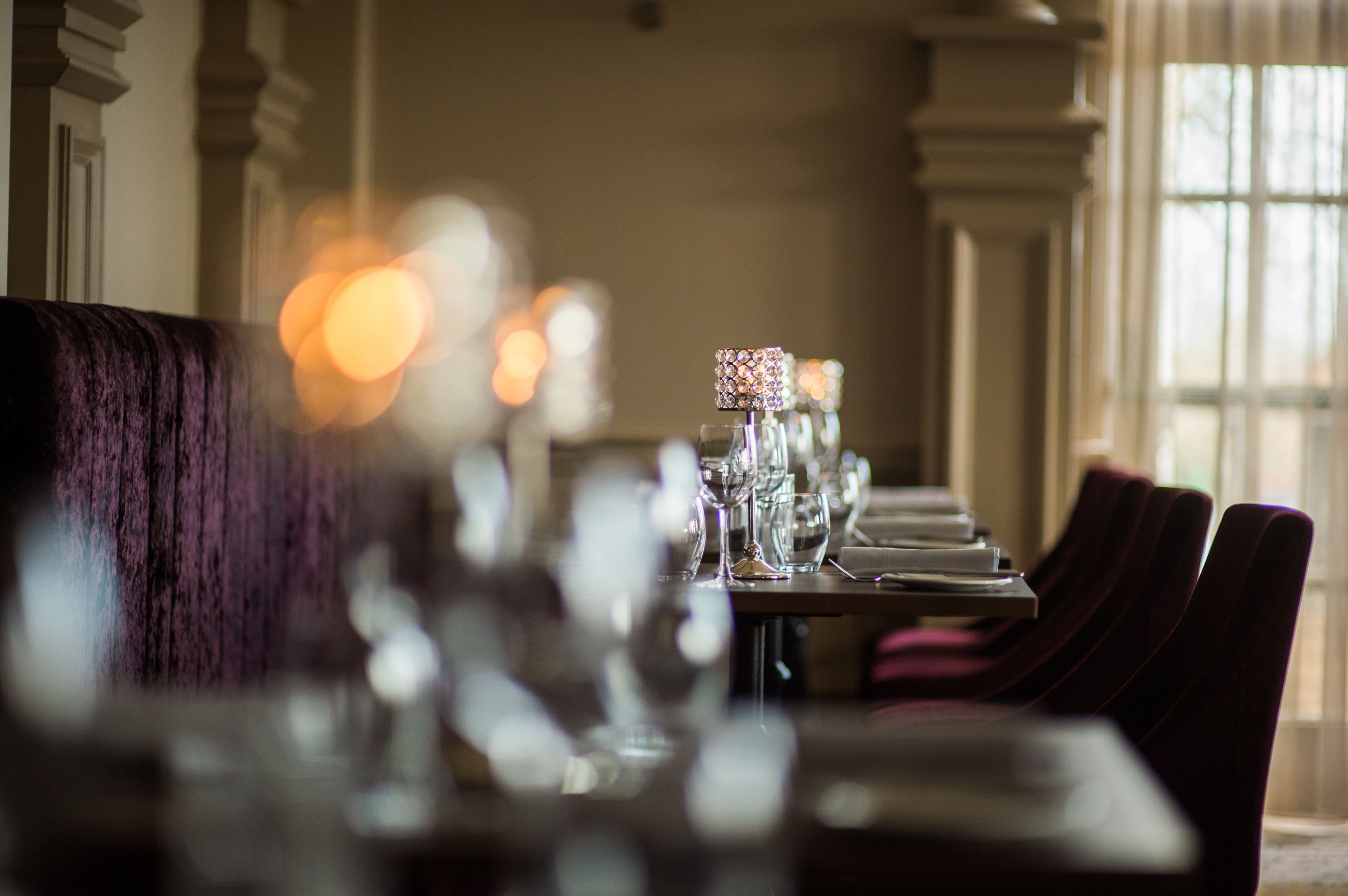 A dining area with a long table set for a meal, featuring clear glassware and a decorative centerpiece.