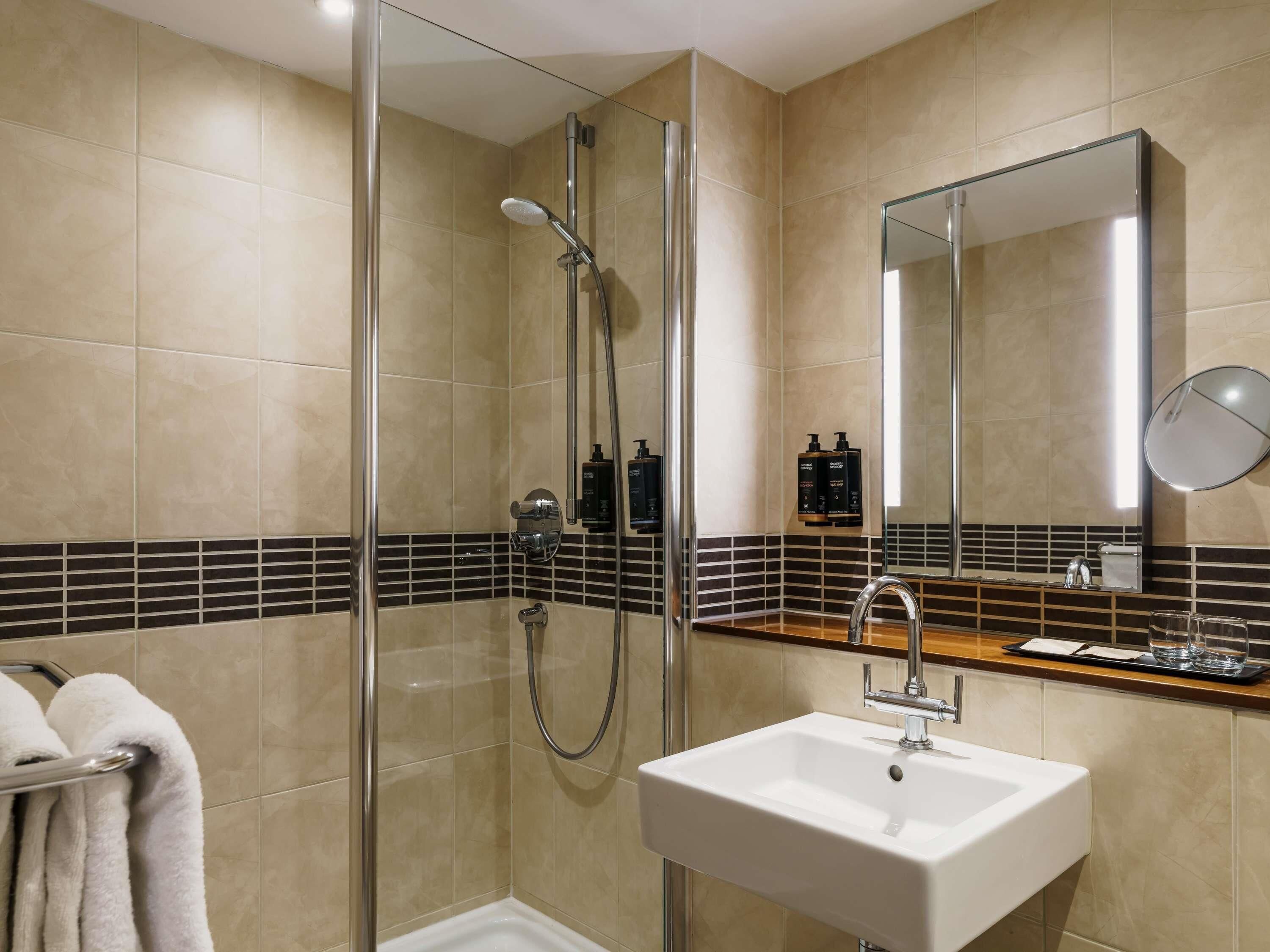 A modern bathroom with a glass-enclosed shower, a sink, and a mirror.