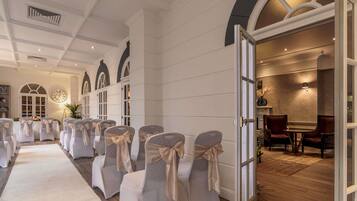 A hotel room with a long corridor leading to a seating area, a dining area, and a view of the outside.