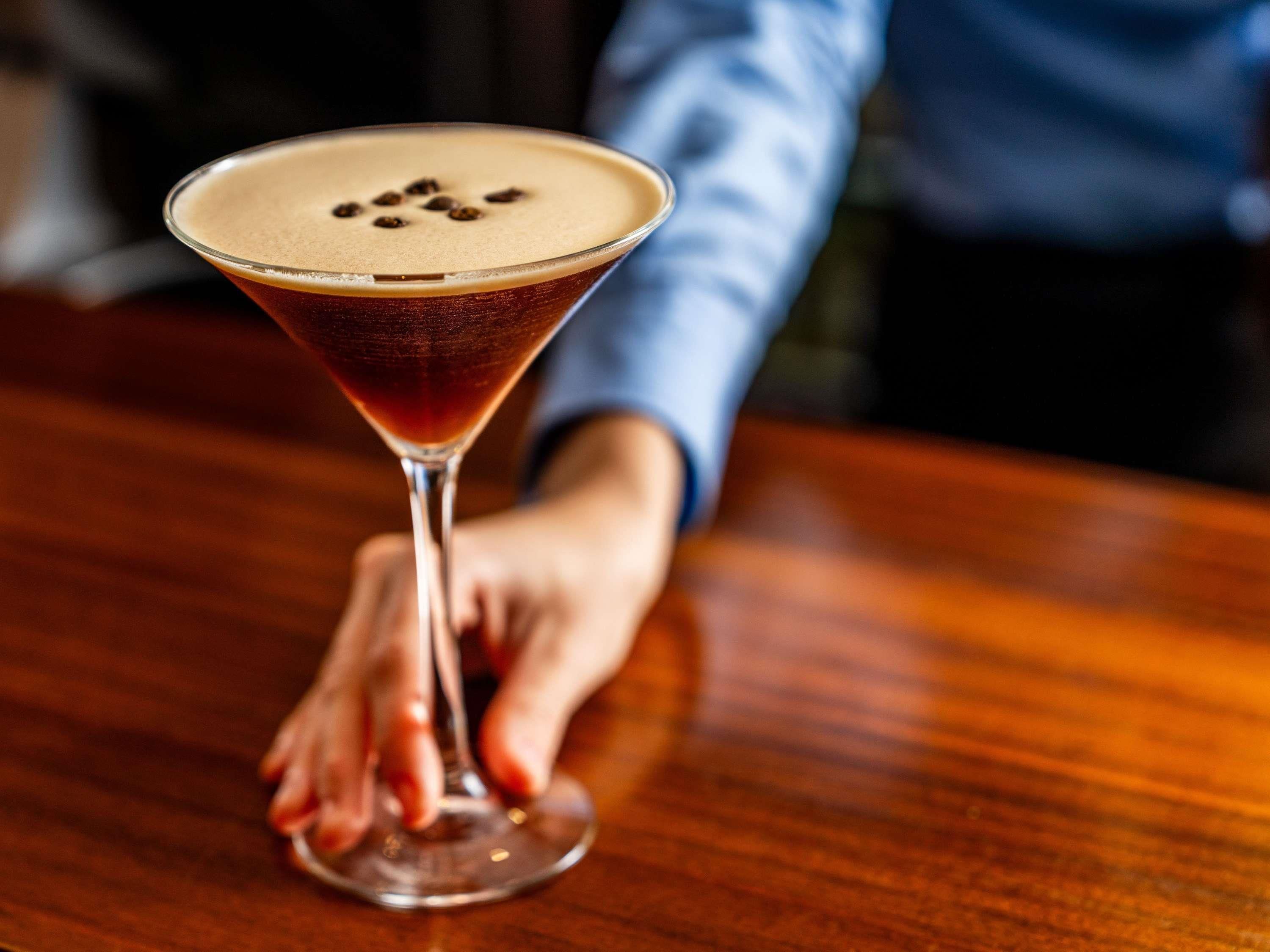 Una copa de martini con una espuma en la parte superior sobre una barra de madera.
