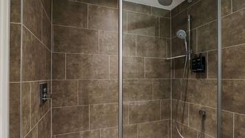 A modern shower area with a glass door, a handheld showerhead, and a wall-mounted faucet.