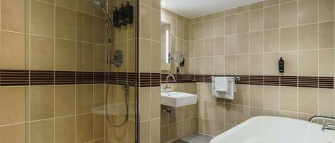 Un baño moderno con ducha a ras de suelo, una bañera independiente, un lavabo y un perchero para toallas.