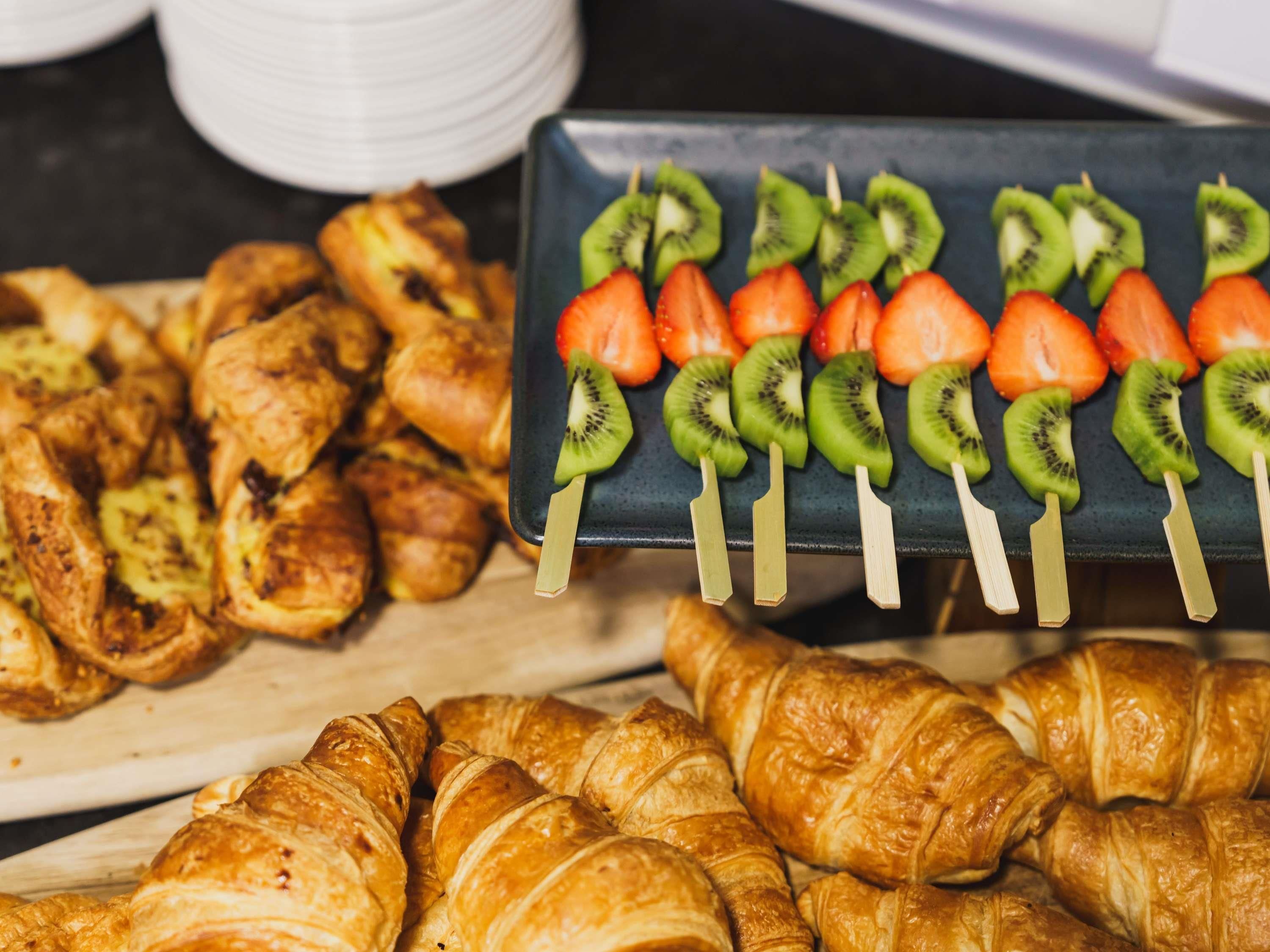 Un buffet proposant des croissants, des brochettes de fruits et des pâtisseries.
