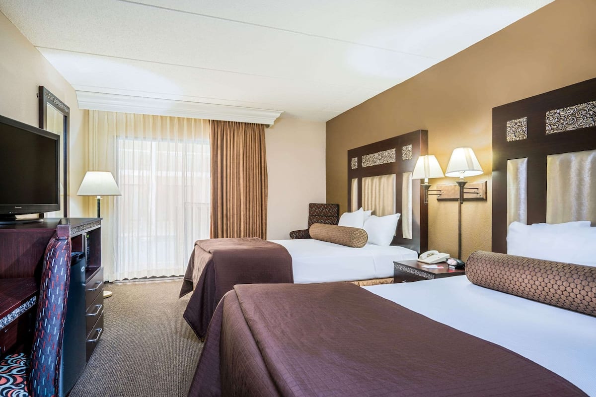 Une chambre d’hôtel avec deux lits, une télévision, un bureau et une lampe.