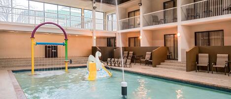 En indendørs swimmingpool med rutsjebane, liggestole og en balkon med gelænder.