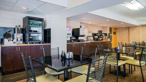 A hotel dining area with a buffet setup, including a refrigerator, coffee machines, and a variety of food items. - Ramada Hotel & Conference Center by Wyndham Plymouth (Plymouth)