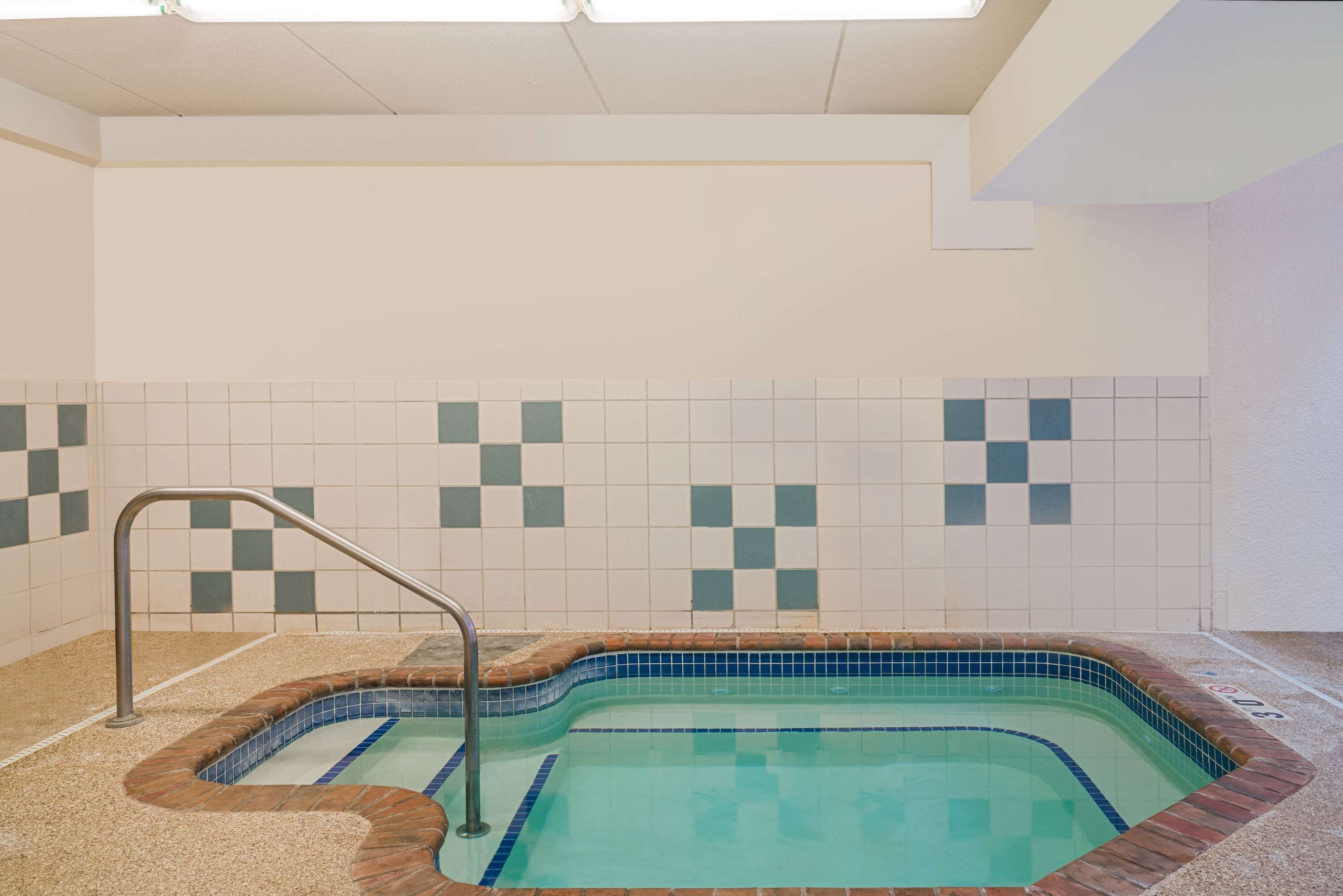A small indoor swimming pool with a tiled wall and a metal ladder.