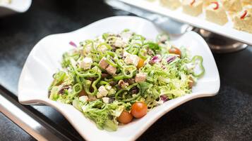 A white, square-shaped plate with a salad containing green peppers, tomatoes, and other vegetables.