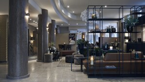 A modern lobby with a central seating area, a coffee bar, and a reception desk.