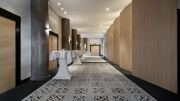 A hallway with a patterned carpet, a white table with a tablecloth, and wooden paneling on the walls.