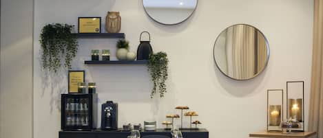 Un comedor moderno con una mesa larga dispuesta para una comida, una máquina de café y una exhibición de pasteles.