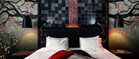A modern bedroom with a large bed, two bedside tables, and a wall with a tree mural.