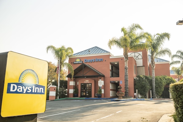 Experience the warm atmosphere of this Days Inn, surrounded by lush greenery and a classic red brick facade.