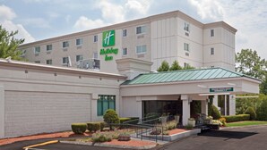 A Holiday Inn hotel with a modern design, featuring a covered entrance and a landscaped front garden.