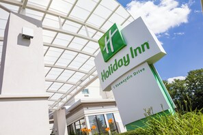 A Holiday Inn sign with a clear view of the building's entrance and a glass roof structure.