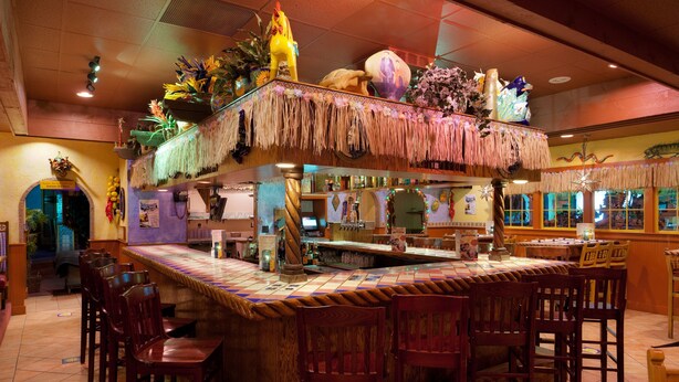 Eine Bar mit Tiki-Bar, Holzstühlen und einer Theke mit dekorativer Dekoration.