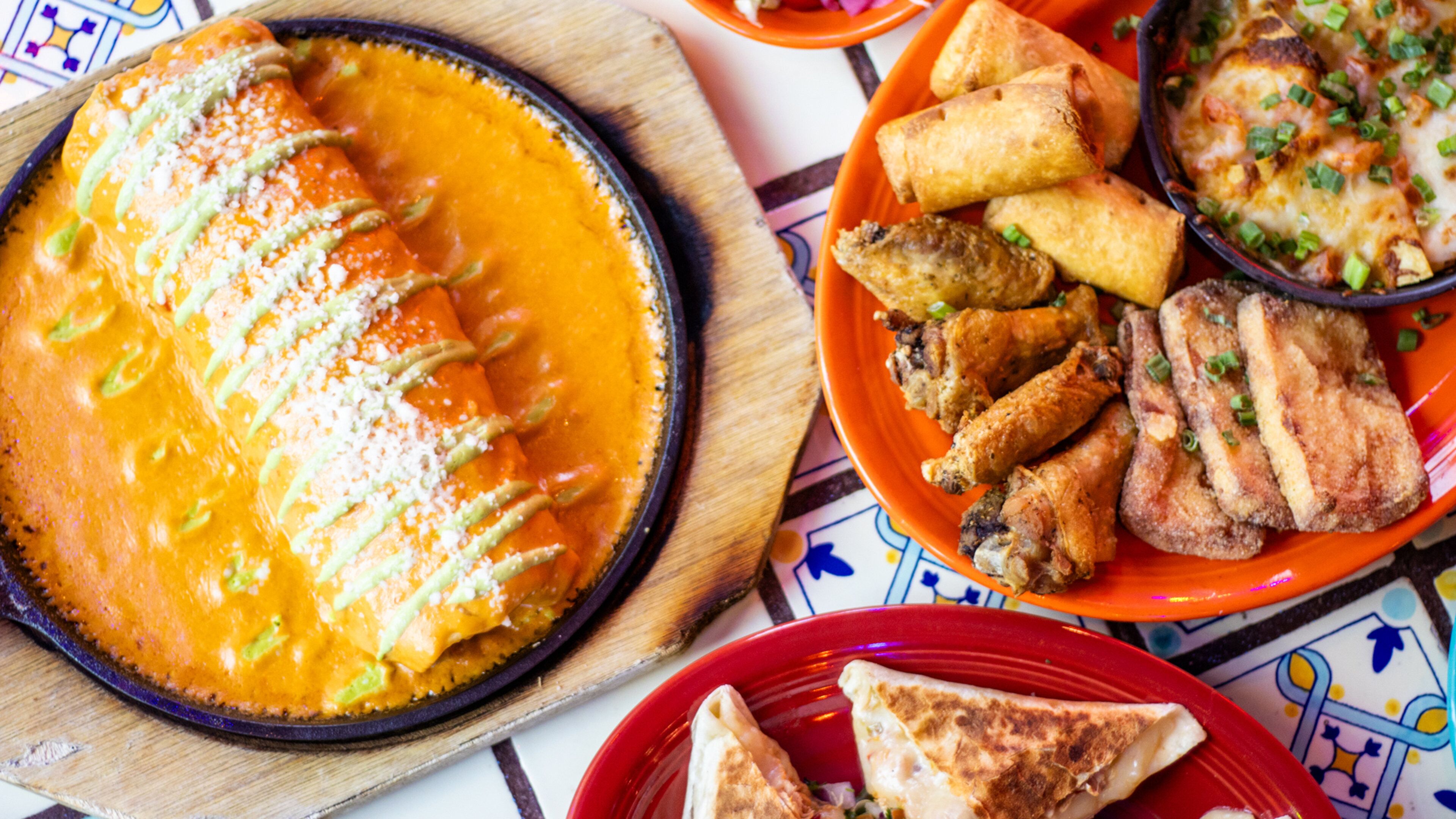 A variety of dishes including enchiladas, fried chicken, and tacos on a table.