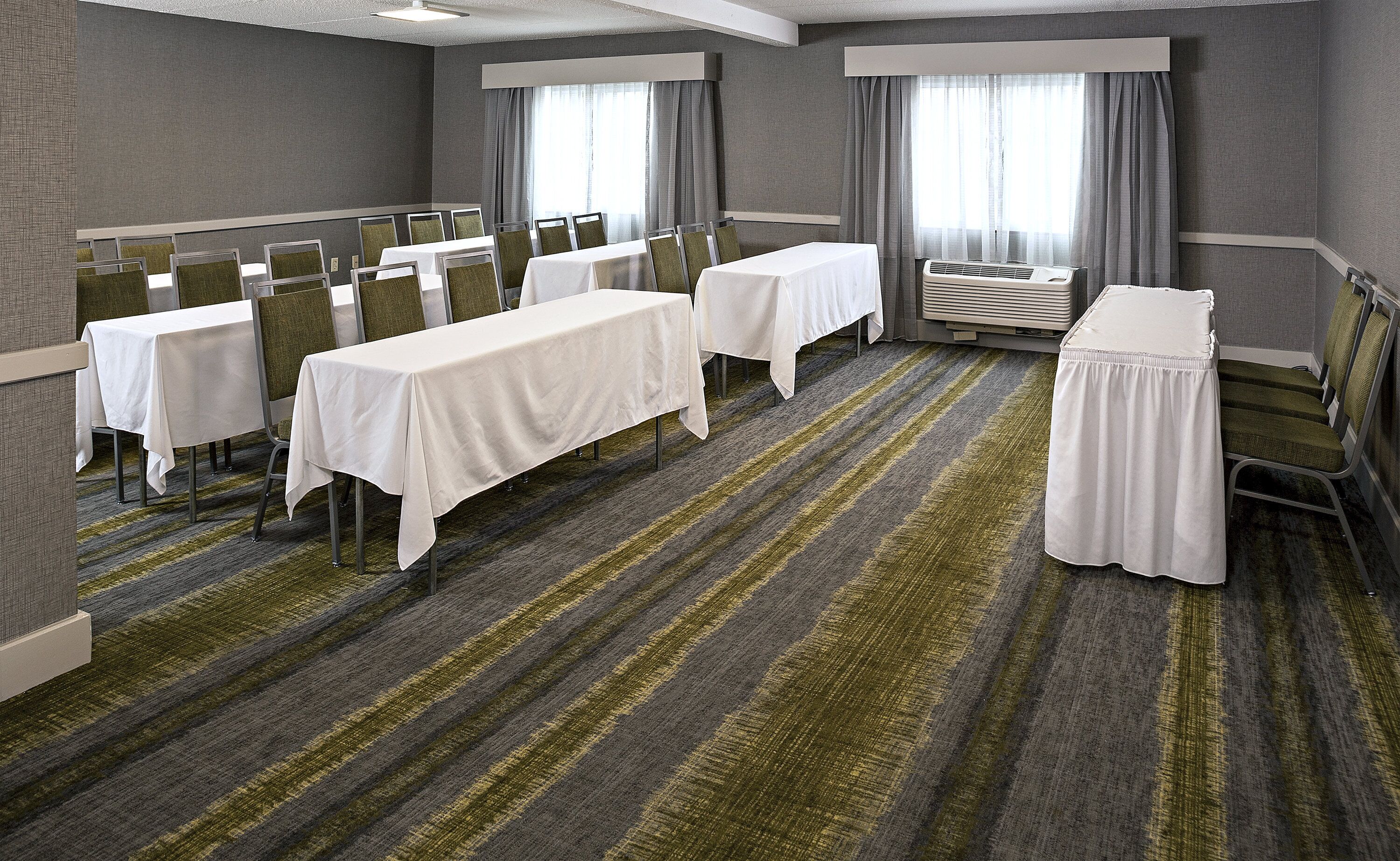 Un salón de conferencias de hotel con varias mesas, sillas y un equipo de aire acondicionado grande.