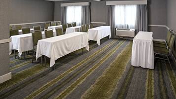 Un salón de conferencias de hotel con varias mesas, sillas y un equipo de aire acondicionado grande.