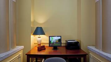 A hotel room with a desk, a lamp, a television, and a printer.