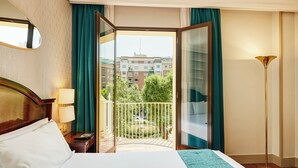A hotel room with a bed, a nightstand, a lamp, a balcony with a view of buildings and trees. - Sercotel Gran Hotel Conde Duque (Madrid)