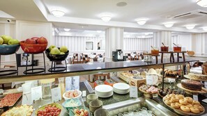 A buffet with various food items, a coffee station, and seating areas in a bright, modern hotel setting. - Sercotel Gran Hotel Conde Duque (Madrid)