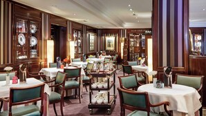 A formal dining area with multiple tables, chairs, and a display of fine china. - Sercotel Gran Hotel Conde Duque (Madrid)