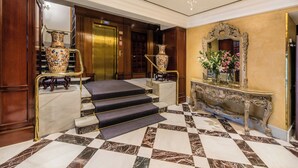A grand lobby with marble flooring, a staircase, a large ornate mirror, and two large vases. - Sercotel Gran Hotel Conde Duque (Madrid)