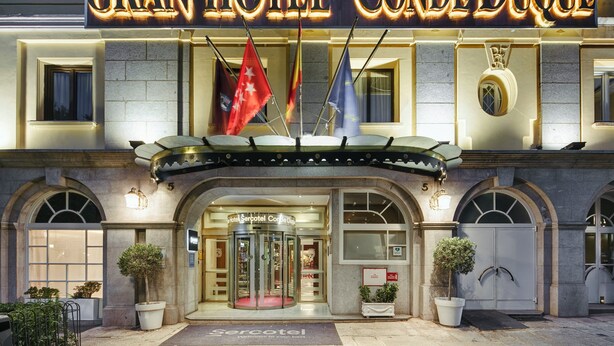 The exterior of the Gran Hotel Conde Duque with a prominent marquee sign, arched windows, and a revolving door entrance. - Sercotel Gran Hotel Conde Duque (Madrid)