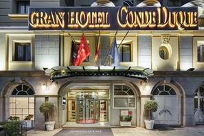 The exterior of the Gran Hotel Conde Duque with a prominent marquee sign, arched windows, and a revolving door entrance. - Sercotel Gran Hotel Conde Duque (Madrid)