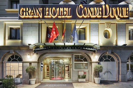 El exterior del Gran Hotel Conde Duque, con un llamativo cartel, ventanas arqueadas y una puerta giratoria.. Sercotel Gran Hotel Conde Duque
