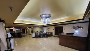 A spacious lobby with a reception desk, seating area, and a modern chandelier. - Wingate by Wyndham Greensboro/Coliseum (Greensboro)