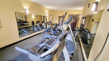 A gym with exercise equipment, a large mirror, and a door in the background.