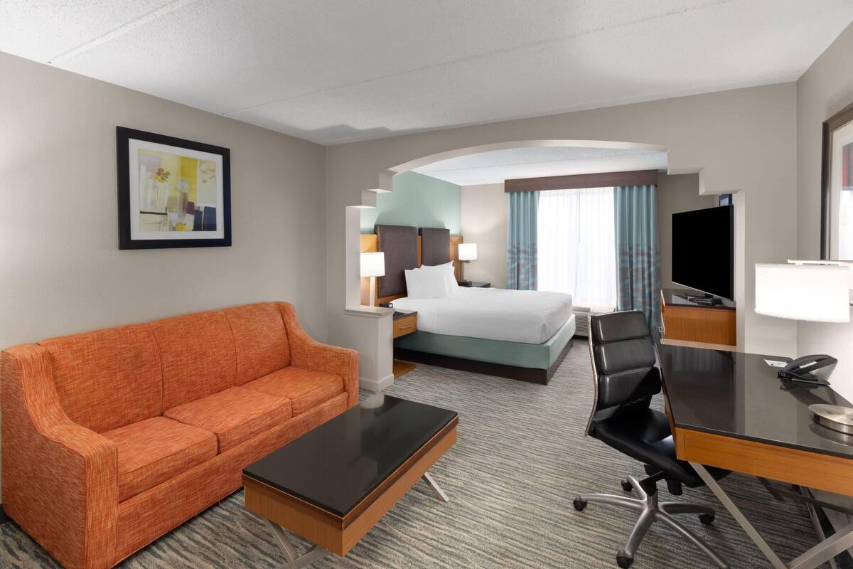 Une chambre d’hôtel équipée d’un lit, d’un bureau, d’une chaise, d’un canapé et d’une télévision.