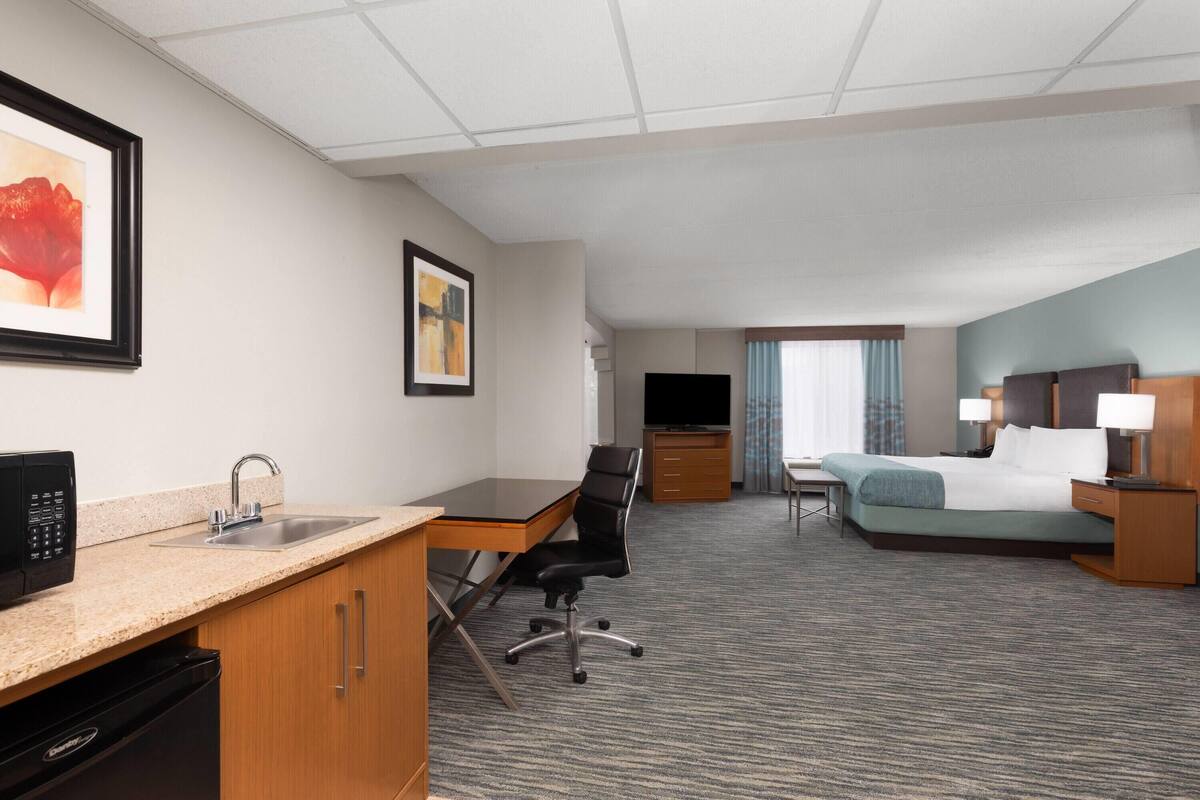 Une chambre d’hôtel équipée d’une kitchenette, d’un lit, d’un bureau et d’une télévision.