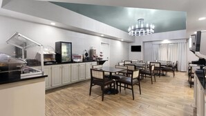 A modern dining area with wooden flooring, white cabinets, and a chandelier. - Wingate by Wyndham Greensboro/Coliseum (Greensboro)