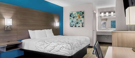 Ein modernes Hotelzimmer mit einem großen Bett, Nachttischen, einem Schreibtisch und einem Spiegel.