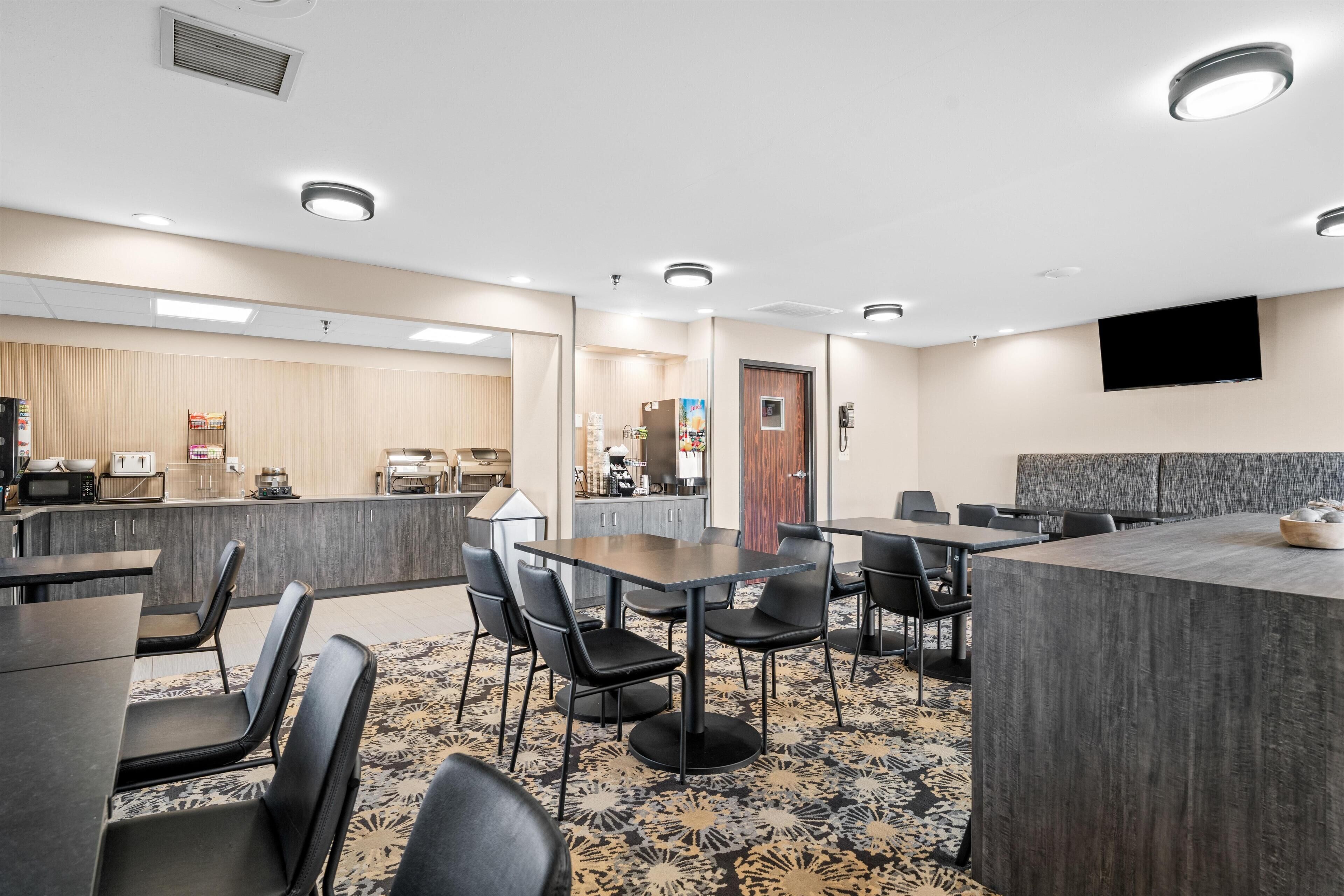 A hotel lobby with a reception desk, seating area, and a kitchenette.